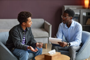 Teenage boy drinking water when talking to adolescent psychologist about his worries and problems